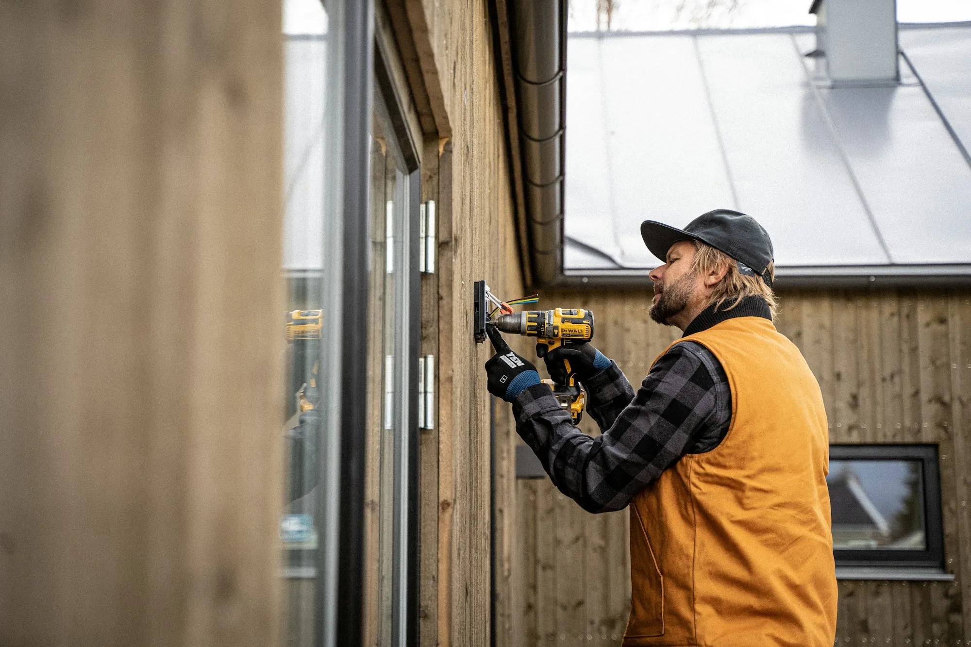 A tradesperson working with a drill on a building exterior