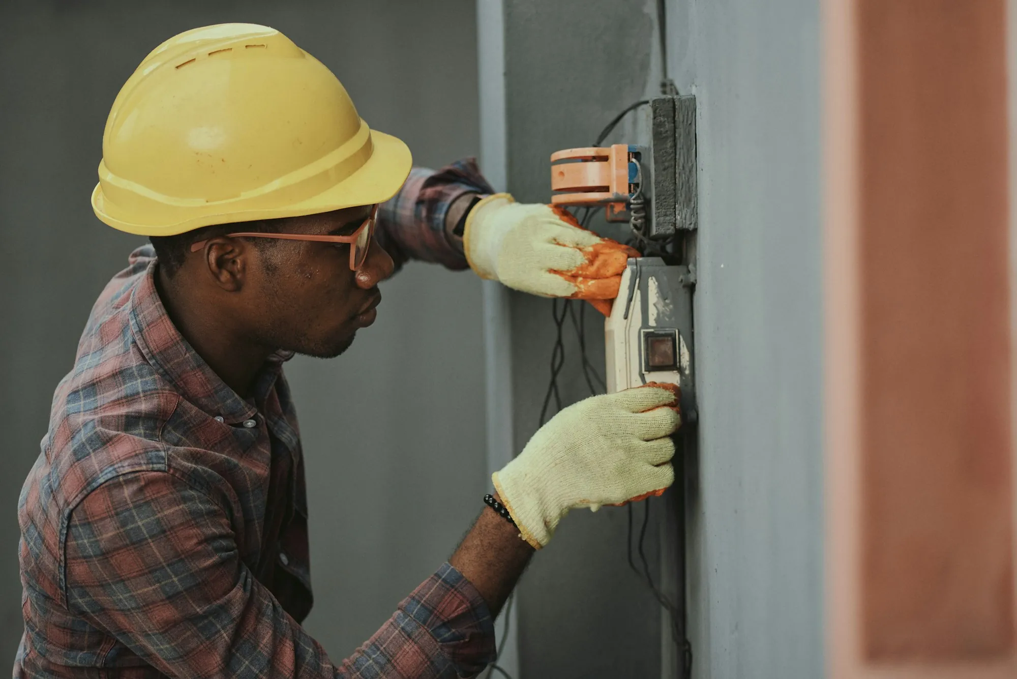 An electrician working at an exterior electrical enclosure